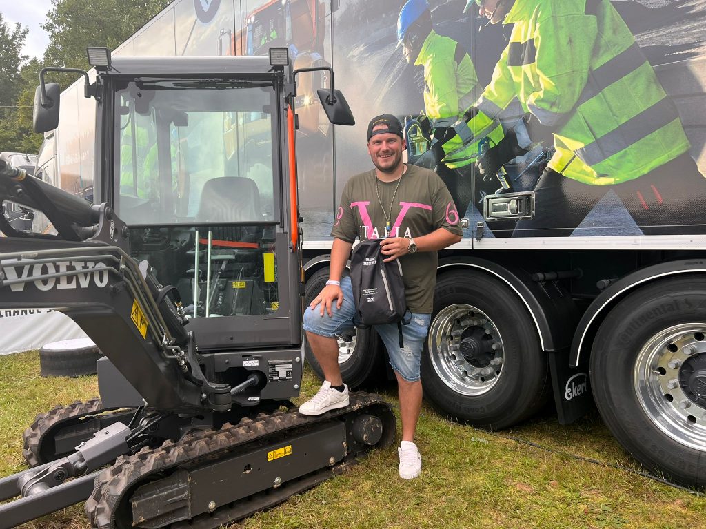 Teilnehmer neben einem Volvo-Minibagger bei einer Veranstaltung