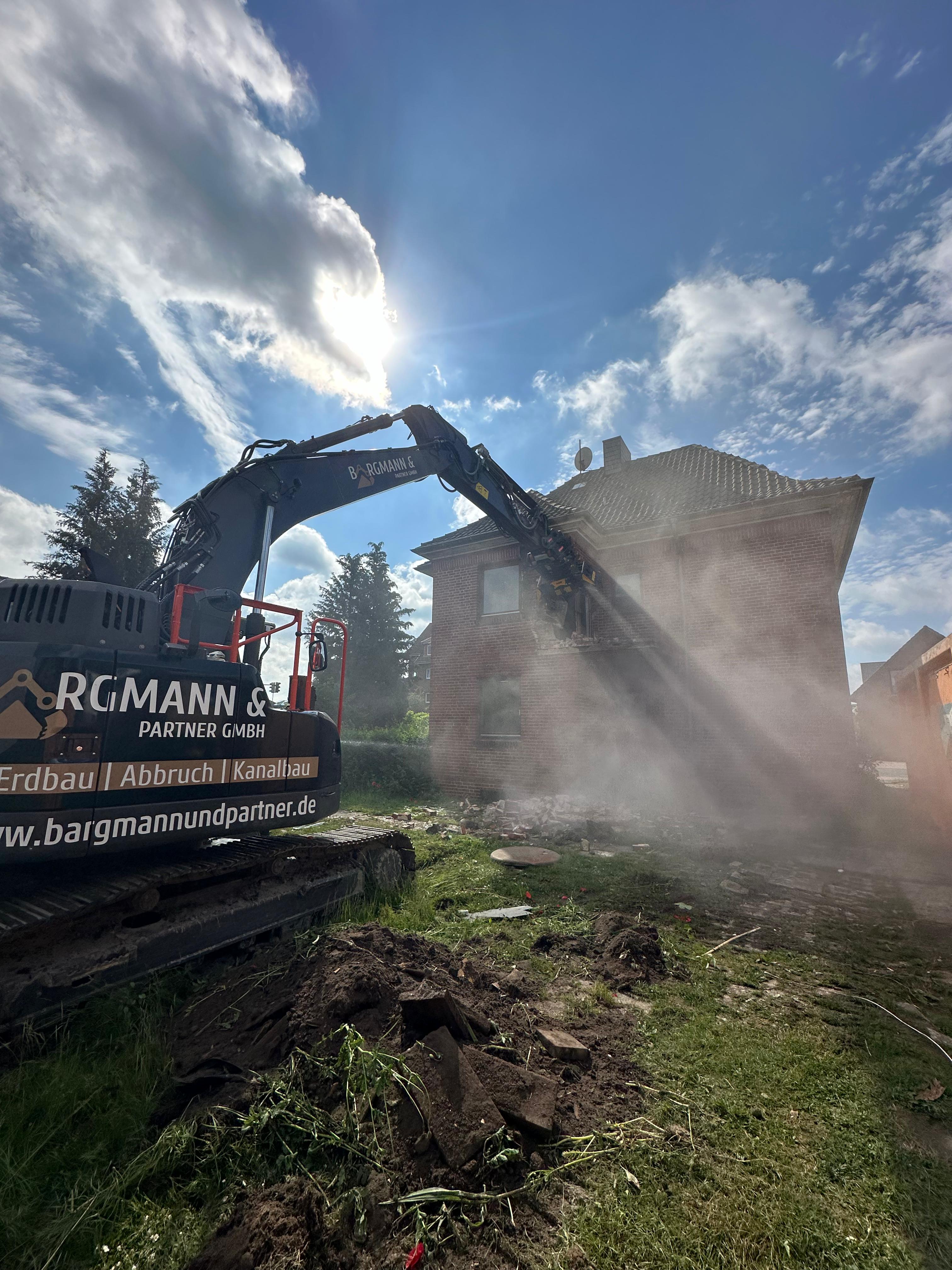 Bagger beim Rückbau eines Gebäudes mit sichtbarer Staubentwicklung