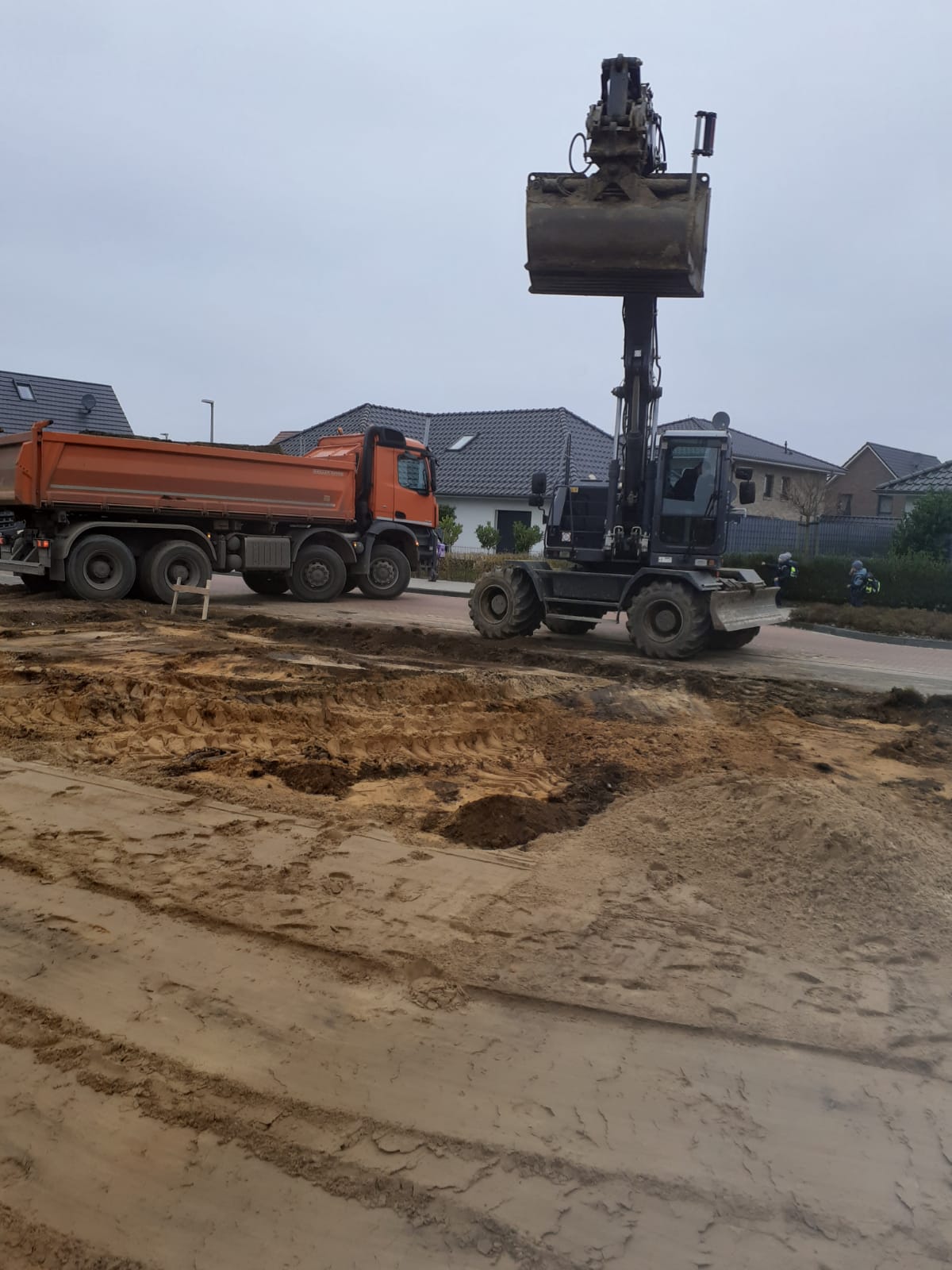 Bagger beim Bearbeiten einer sandigen Baufläche