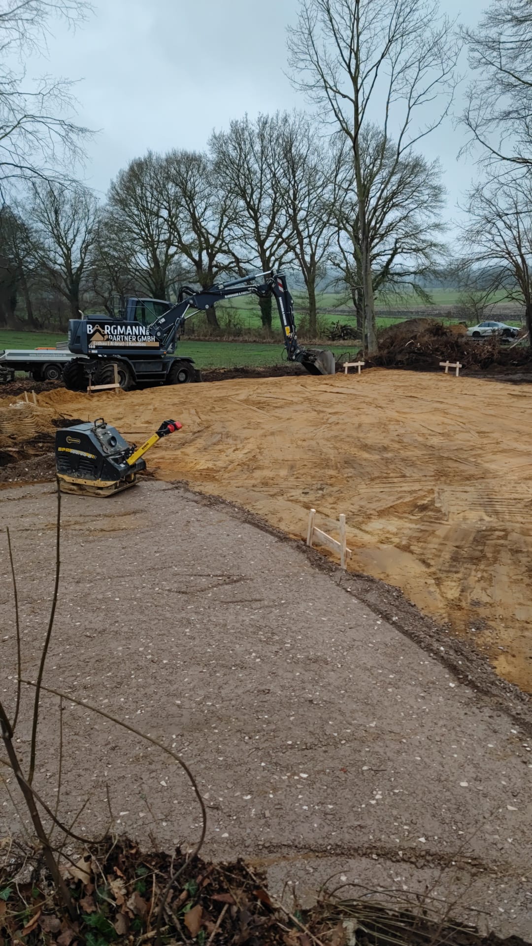 Baustelle mit bearbeiteter Fläche und Bagger im Hintergrund