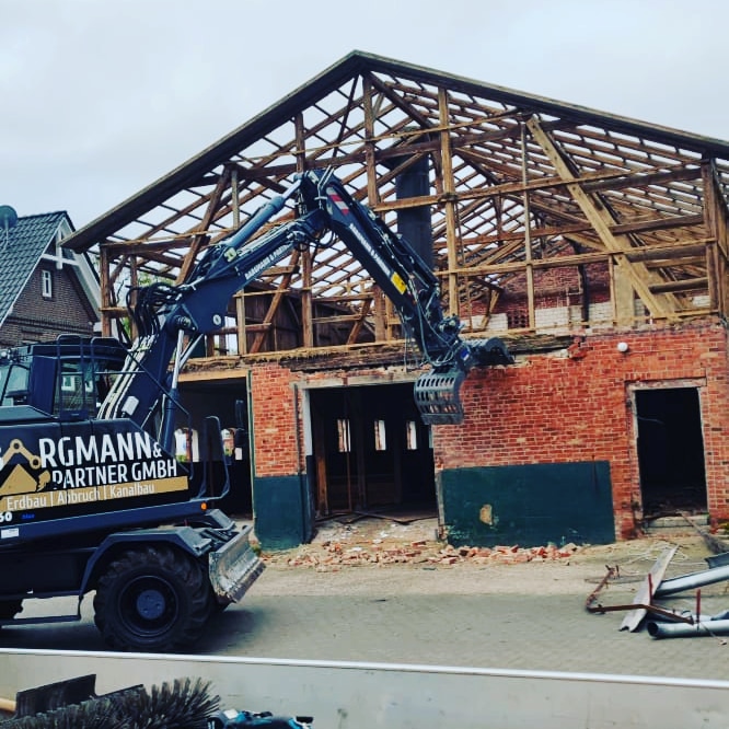 Bagger vor einem teilweise zurückgebauten Gebäude