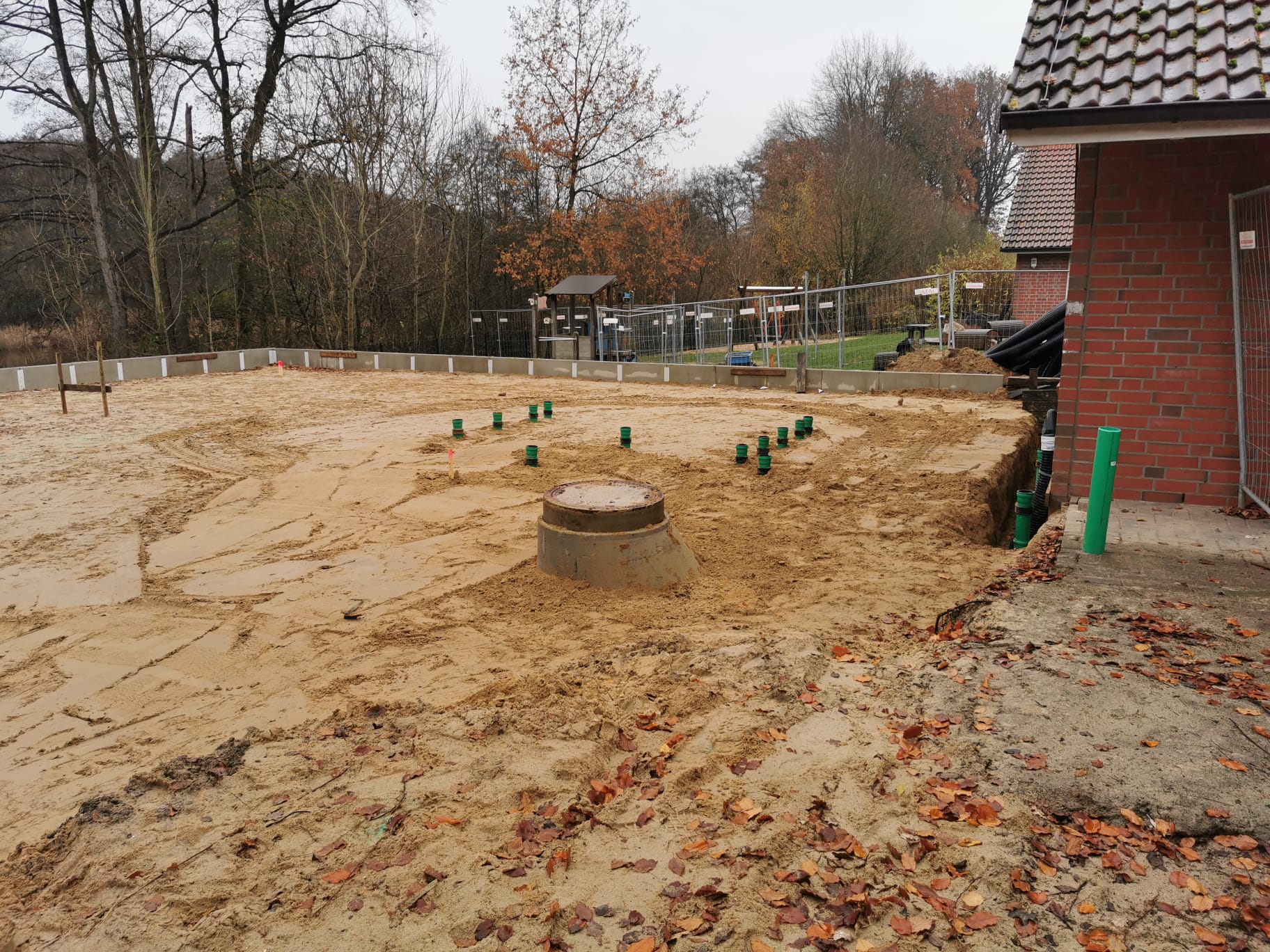 Vorbereitete Baufläche mit einem Schacht und einem Haus im Hintergrund