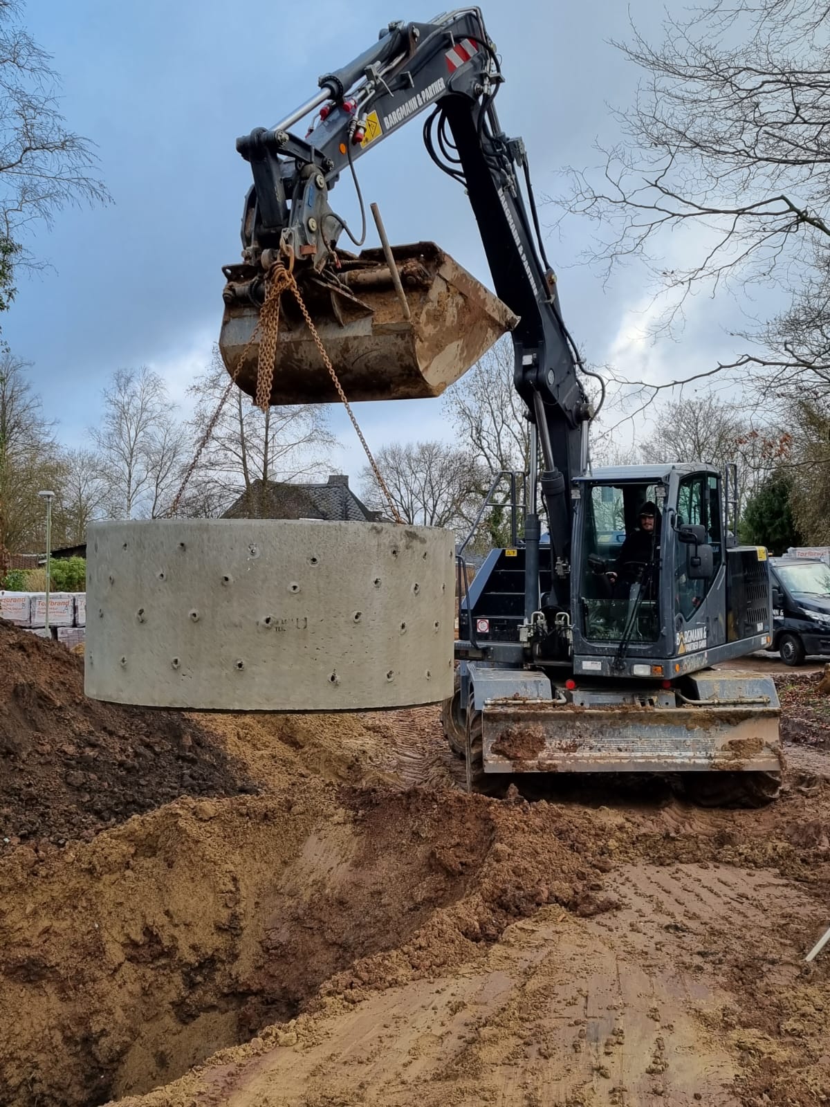 Bagger beim Versetzen eines Betonfertigteils auf einer Baustelle