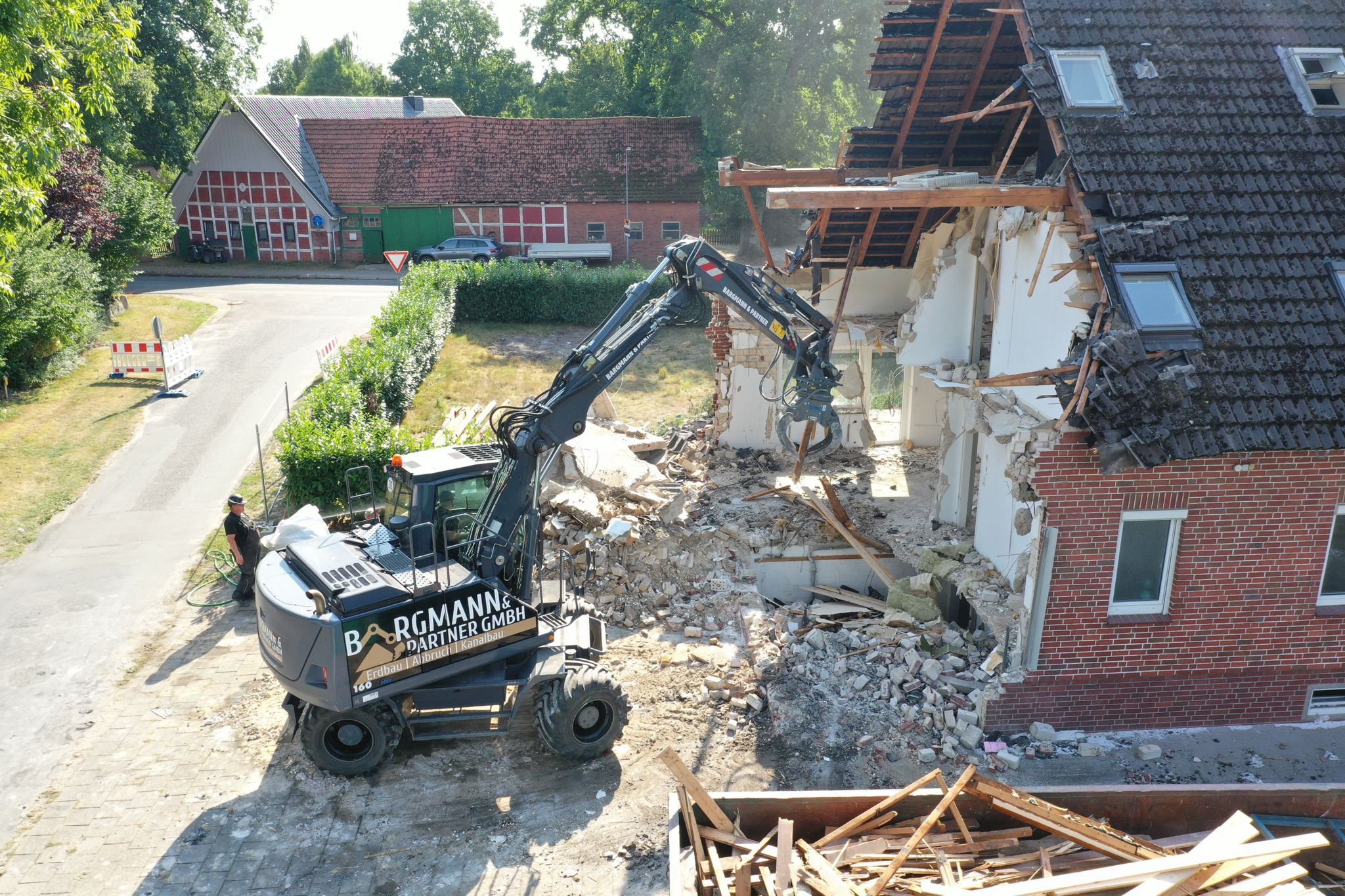 Bagger am teilweise abgebrochenen Dach eines Gebäudes