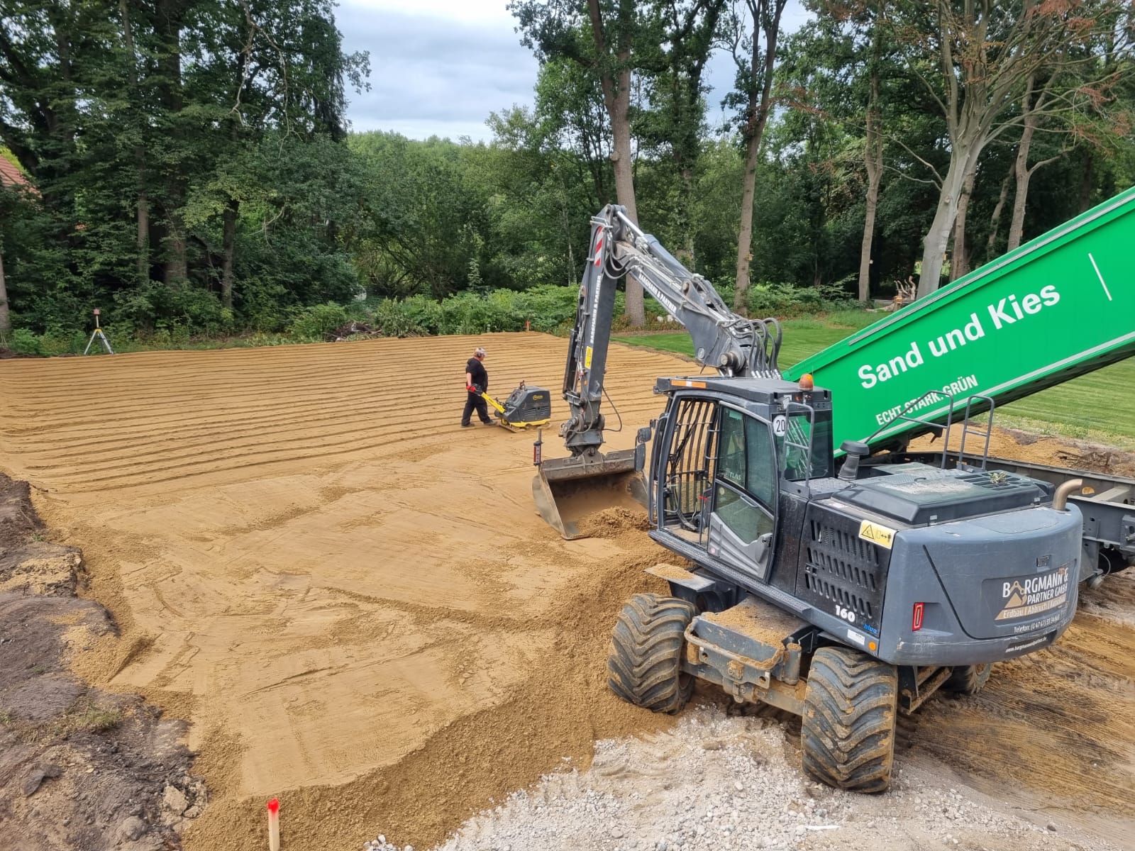 Bagger und grüner Transportanhänger bei Erdarbeiten