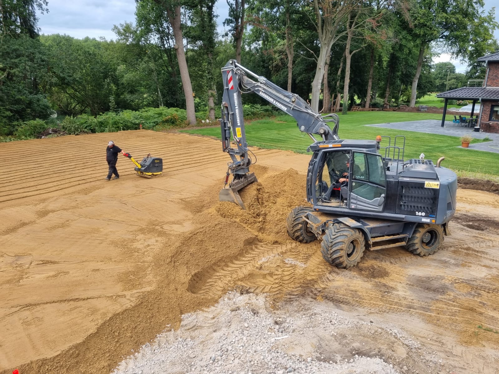 Team und Bagger bei Erdarbeiten auf einer Baustelle