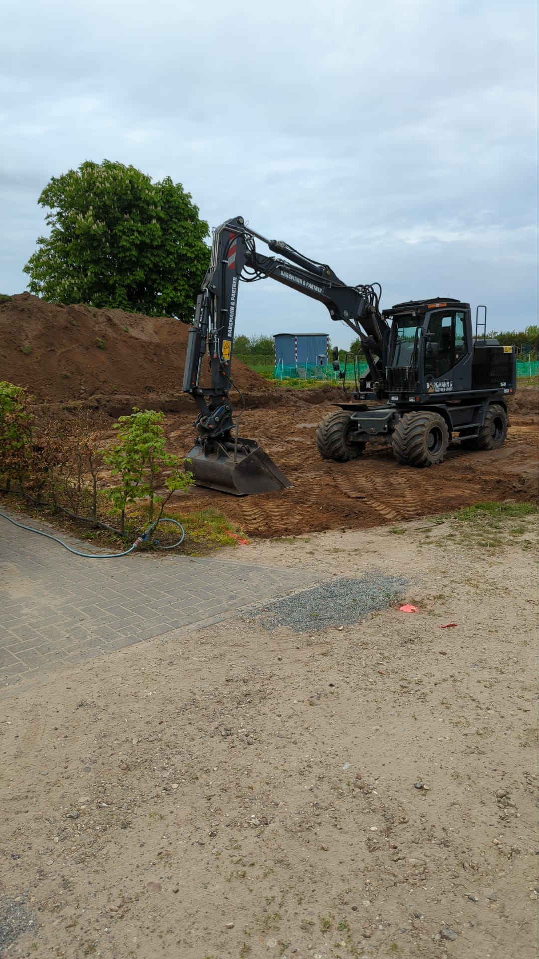 Bagger bei Erdarbeiten am Rand eines Grundstücks