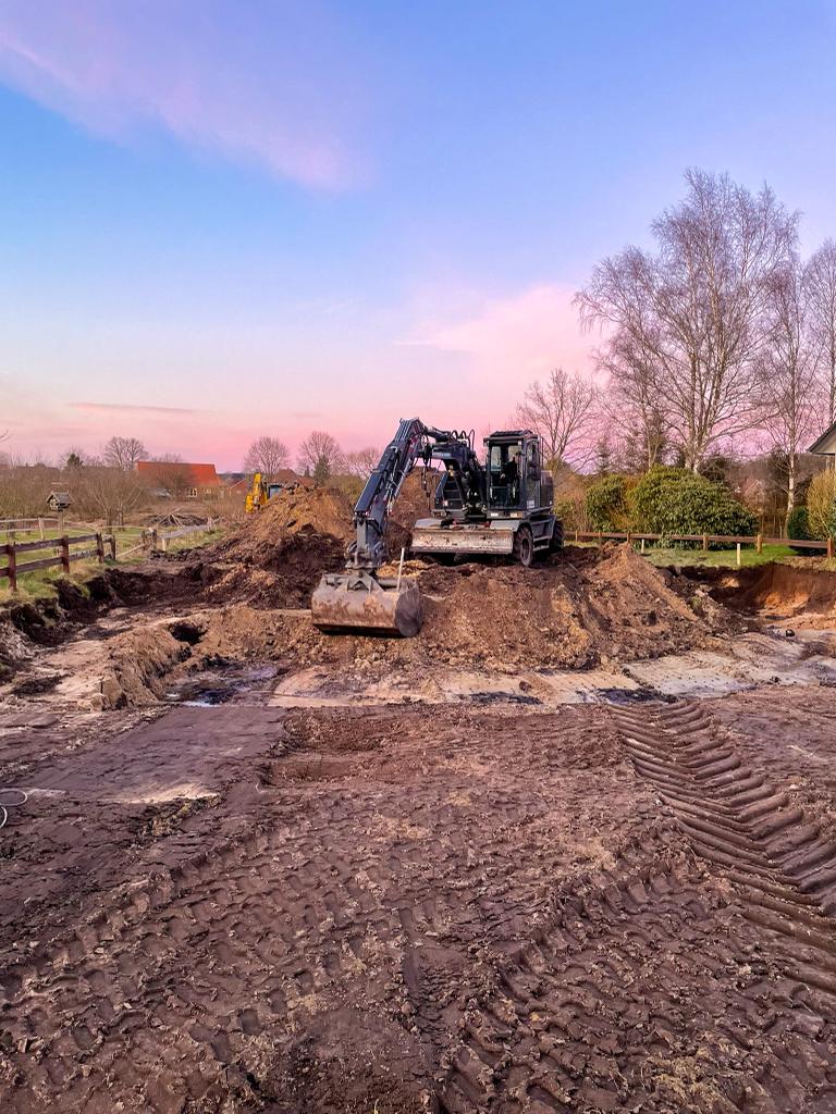 Bagger auf einer Baufläche bei farbigem Himmel